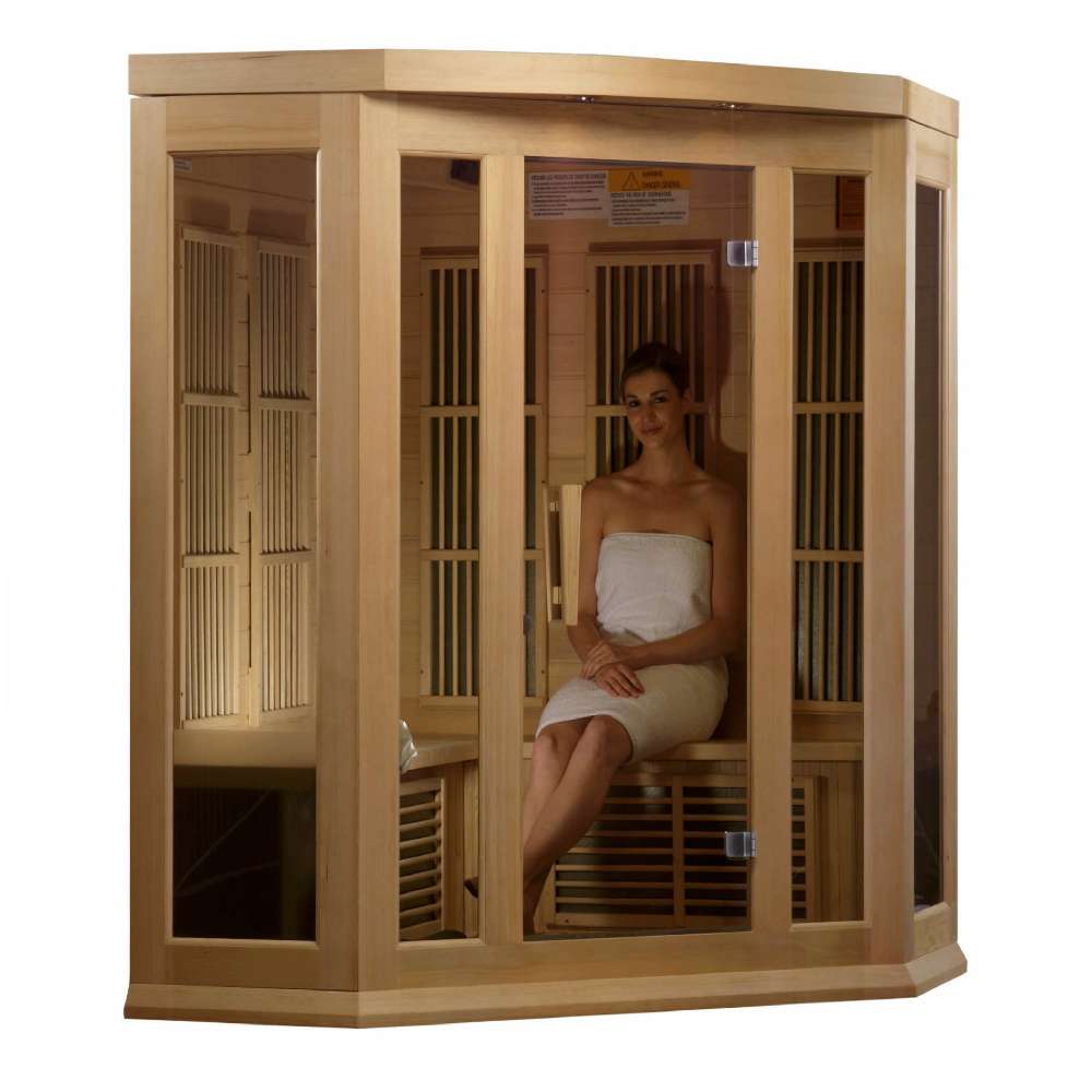 A woman in a white towel sits inside Golden Designs Maxxus 3 Person Low EMF Far Infrared Corner Sauna in Hemlock behind the bronze glass door