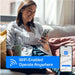 A woman on a sofa uses the Smart Life app on her phone in this WiFi enabled graphic for ACiQ 12000 BTU Essentials 20 SEER2 Single Zone Wall Mount Mini Split Heat Pump System