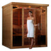 A woman wrapped in a white towel steps out through the open glass door of Golden Designs Monaco Near Zero EMF Far IR Sauna