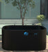 A Dreampod Cold Plunge Barrel FLEX with Chiller in a minimalist outdoor setting with a small tree in the background