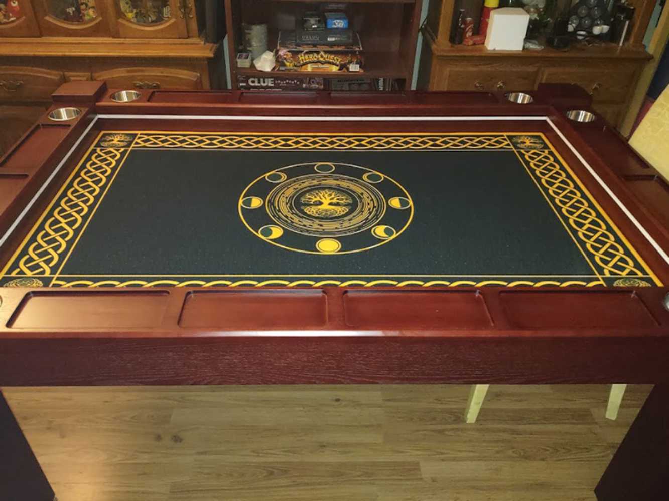 A Game Theory Tables Origins Lit table featuring a Celtic-inspired design on a dark green surface, framed by rich wood and cup holders