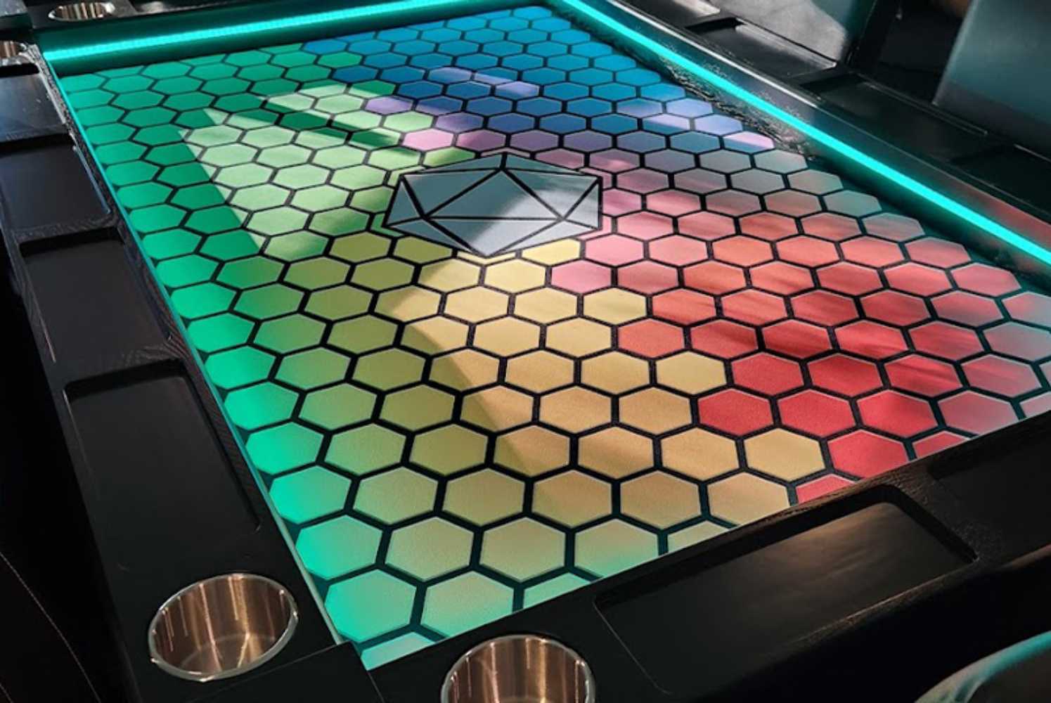 A Game Theory Tables Origins Lit table with a colorful hexagon pattern in vibrant shades, bordered by bright LED lights and cup holders