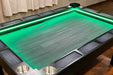 A Game Theory Tables Origins Lit table with a simple green wood-patterned surface, surrounded by cup holders and softly glowing LED lighting