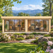 Straight-on view of the ALU Concept Lounge 44B Freedom Office in western North Carolina, surrounded by rhododendrons, native woodland and layered Blue Ridge Mountains, with professionals working behind its two expansive glass sections.