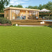 A cozy garden scene with patio, furniture, and greenery surrounds the sunlit GardenHouse24 USA ALU Concept Lounge 70B Garden Room