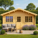 A GardenHouse24 USA Sean 44 Garden Room with a peaked roof, front door, two symmetrical windows, patio seating, and blooming lavender plants