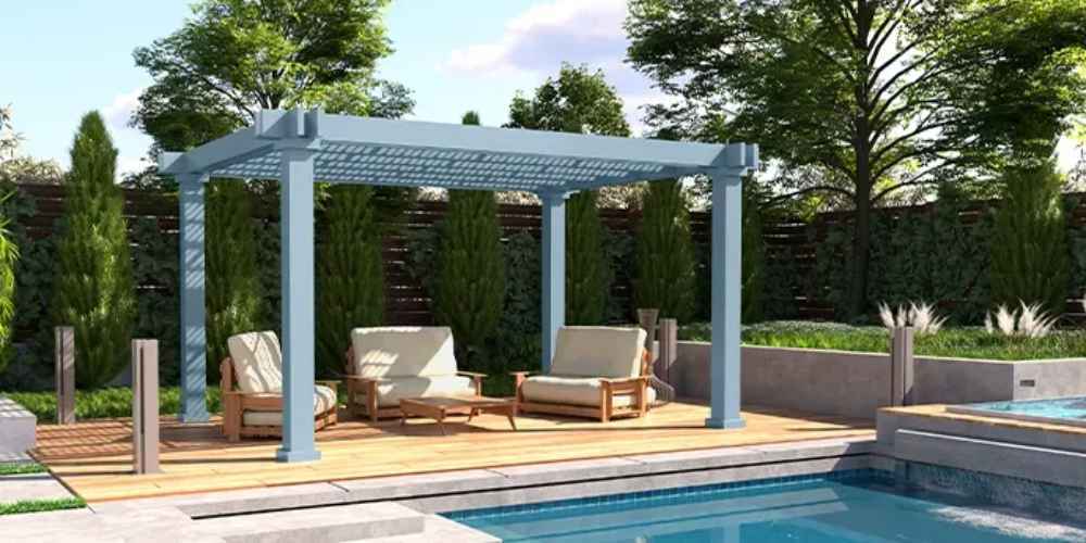 A Structureworks Reverie Fiberglass Pergola covers an outdoor seating area near a pool, surrounded by lush greenery