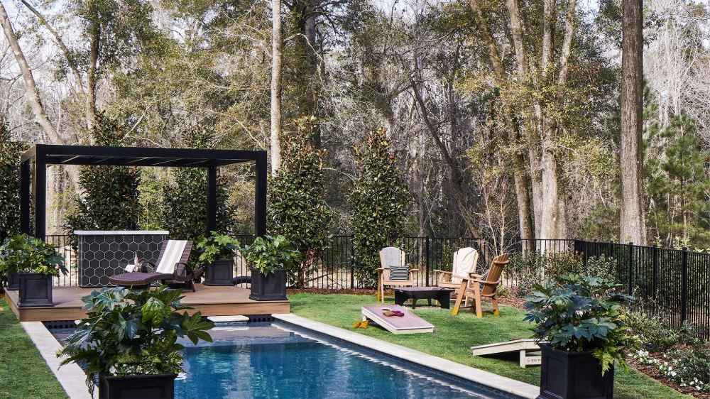 A Structureworks Shadow Trex Pergola stands elegantly over a poolside deck with lounge chairs and lush planters
