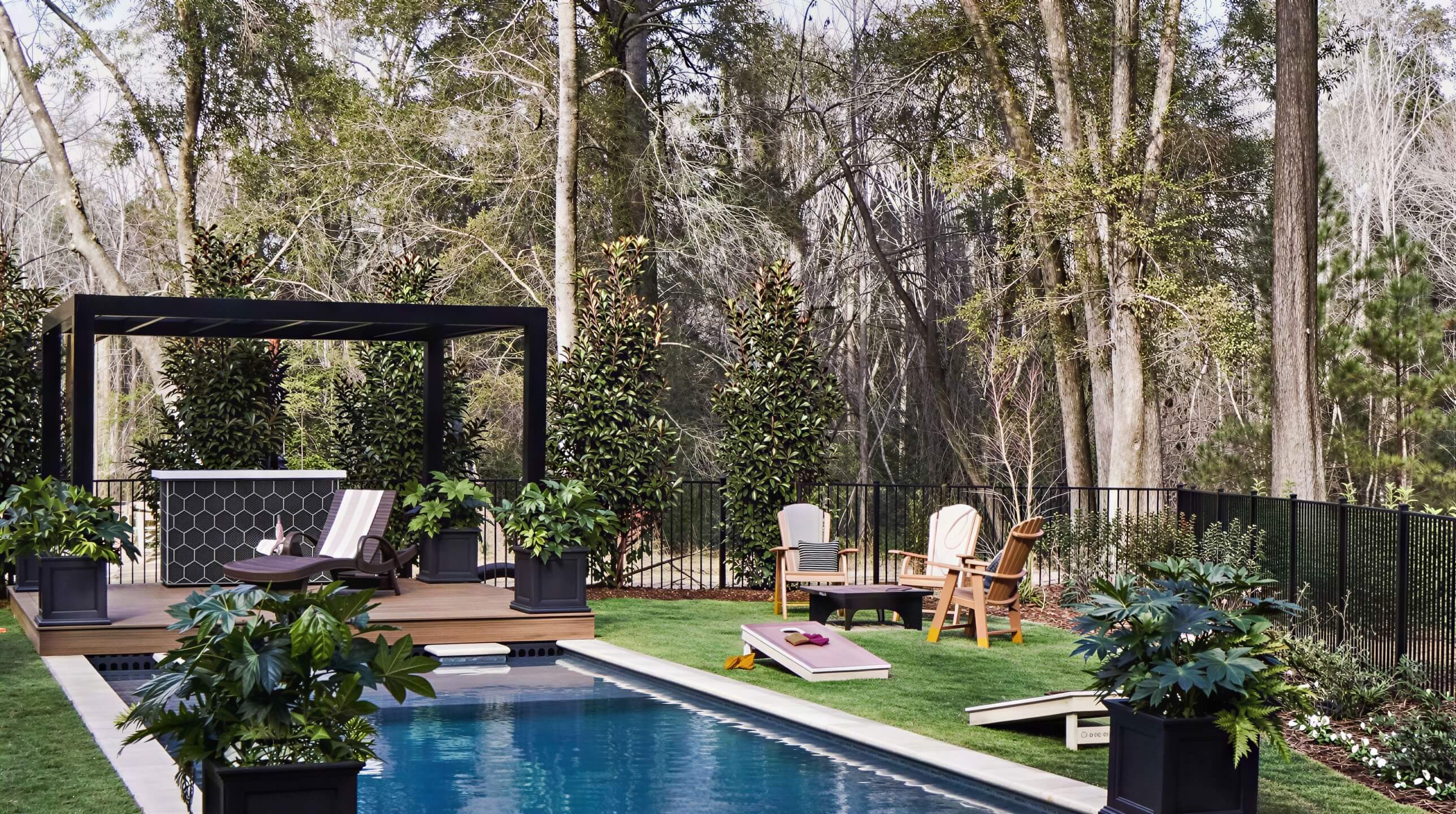 A Structureworks Shadow Trex Pergola stands elegantly over a poolside deck with lounge chairs and lush planters