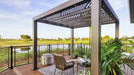 A Structureworks Shadow Trex Pergola with angular slats shades a serene outdoor balcony set for drinks