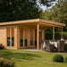 A beautiful outdoor setting showcases the GardenHouse24 USA Taunus 70 VD Garden Room with a modern flat roof, glass doors, and a covered dining area