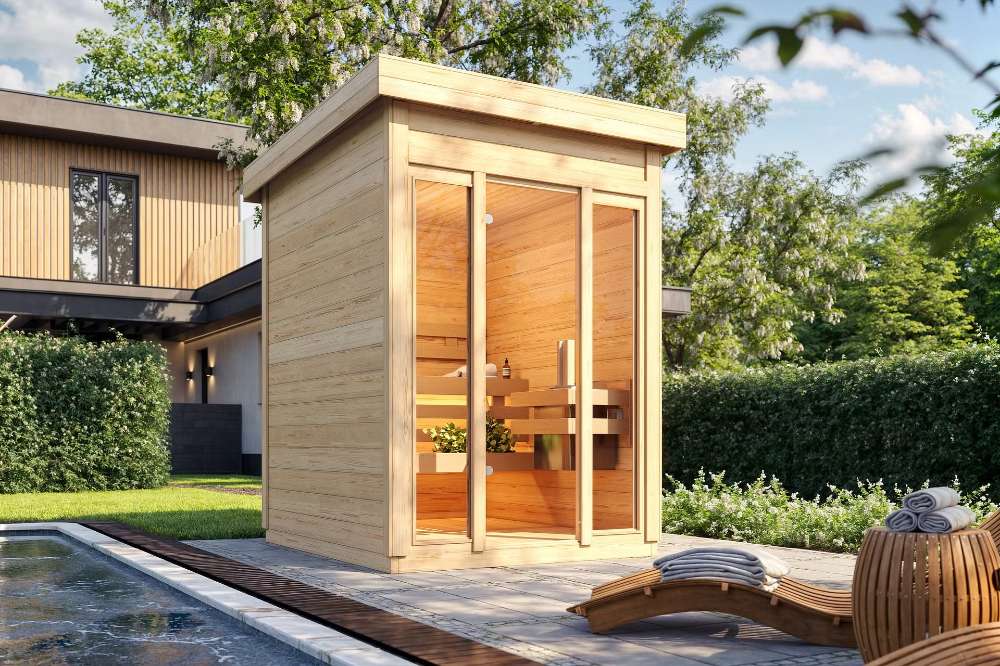 A bright outdoor setting highlights Sawmill Structures TS TwoSauna Sauna, its smooth wooden frame glowing warmly beside a calm pool and lounge area