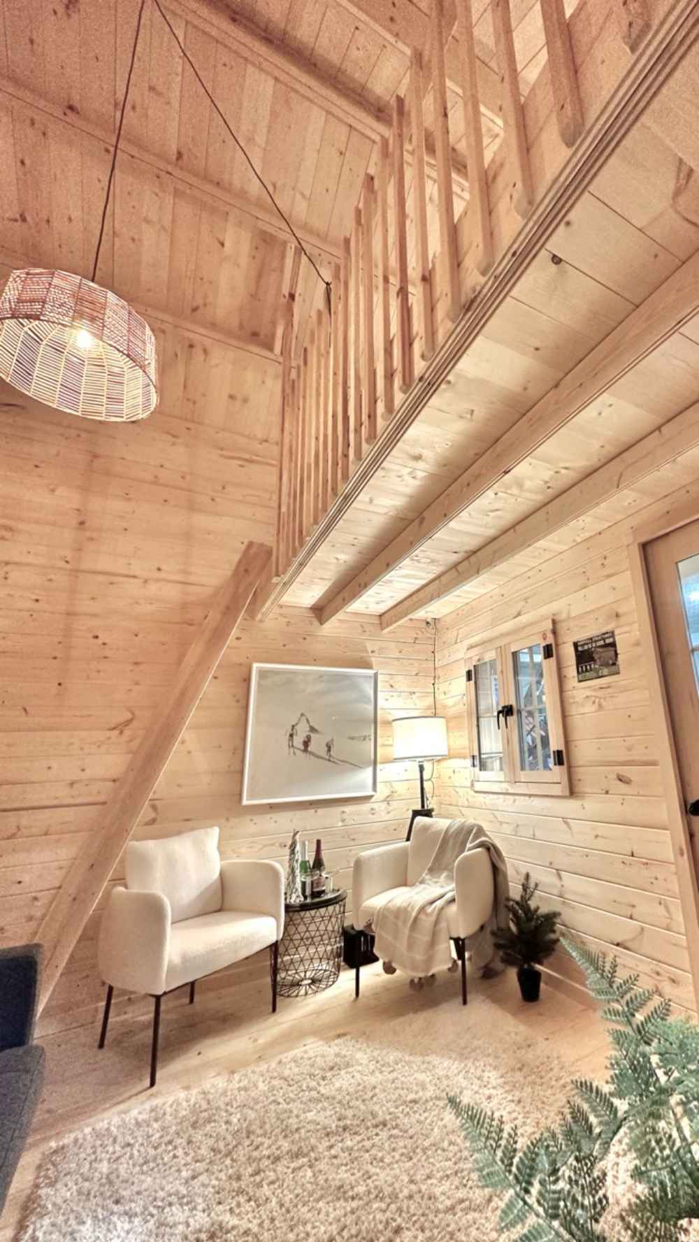 A bright sitting area with two white chairs and soft lighting rests beneath a loft in the Sawmill Structures Ontario Grand Loft 107 SD Garden Room