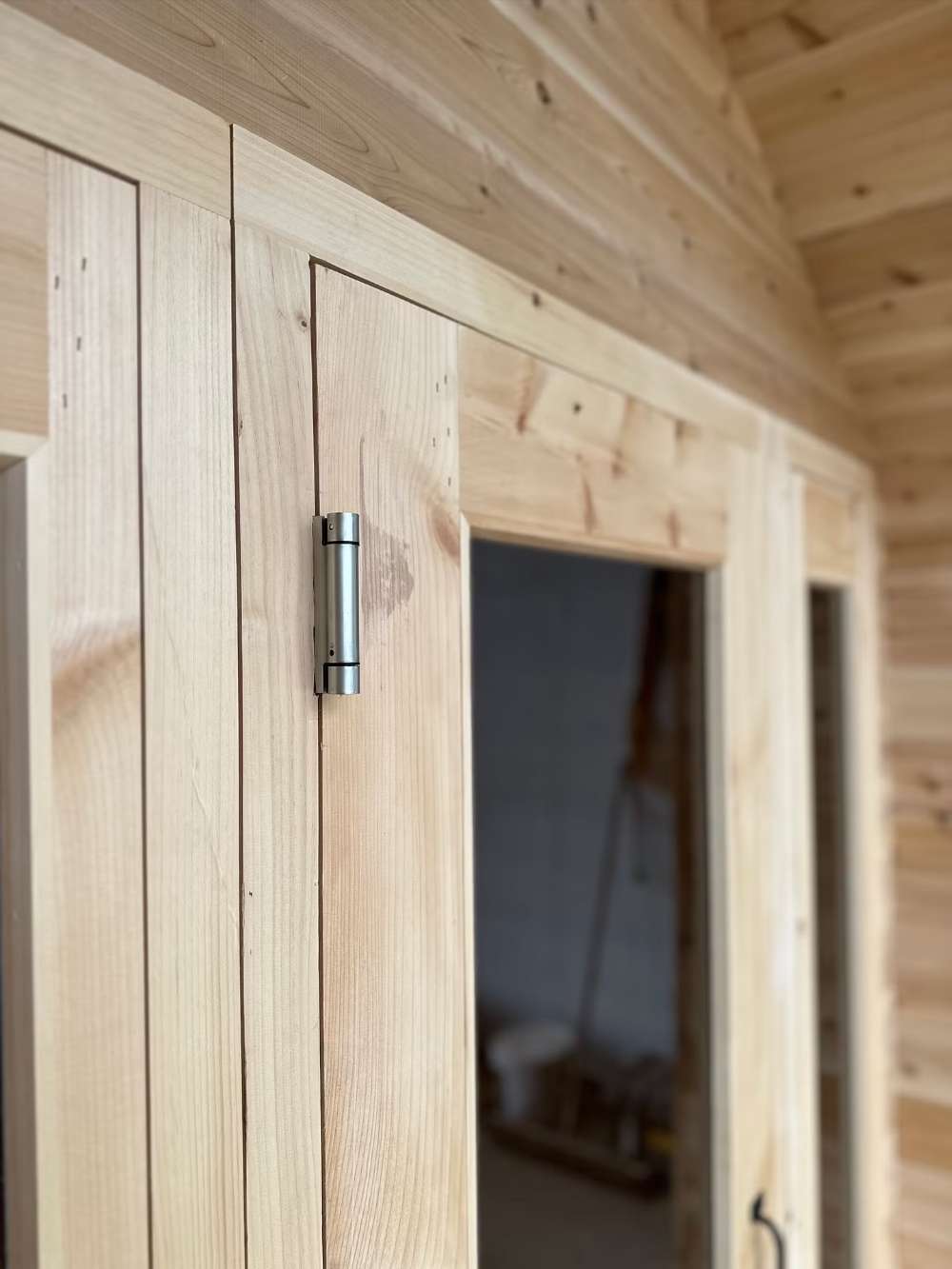 A close-up of the sturdy door hinge and smooth wood grain on Sawmill Structures CabinSauna