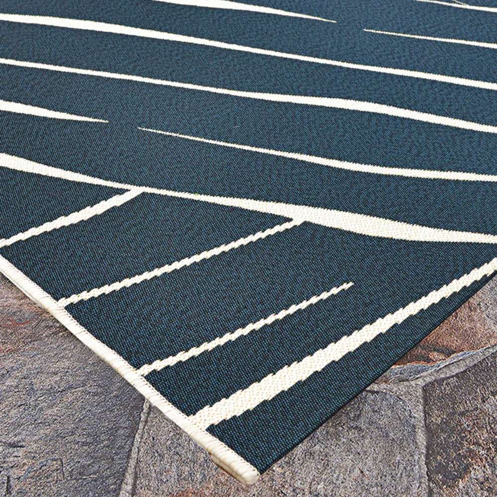 A close-up view of the edges and intricate texture of Couristan Dolce Indoor/Outdoor Rug - Parquet/Ink resting on a stone floor