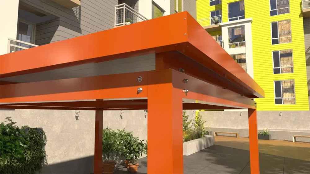 A close-up view of the orange Structureworks Pavilion Trex Pergola shows the sturdy corner post and metallic fasteners against a sunny building facade