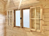 A close-up view of wooden-framed double windows with frosted glass and internal shutters inside the Sawmill Structures Harvest Grand Bungalow 107 Garden Room