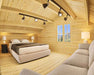A cozy bedroom with a sloped wooden ceiling and modern lighting features a plush bed and couch inside Sawmill Structures The Northwood Grand SD 70mm Garden Room