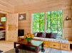 A cozy bench with storage and pillows faces large forest-view windows in the Sawmill Structures Edwin Lake House 70MM Garden Room