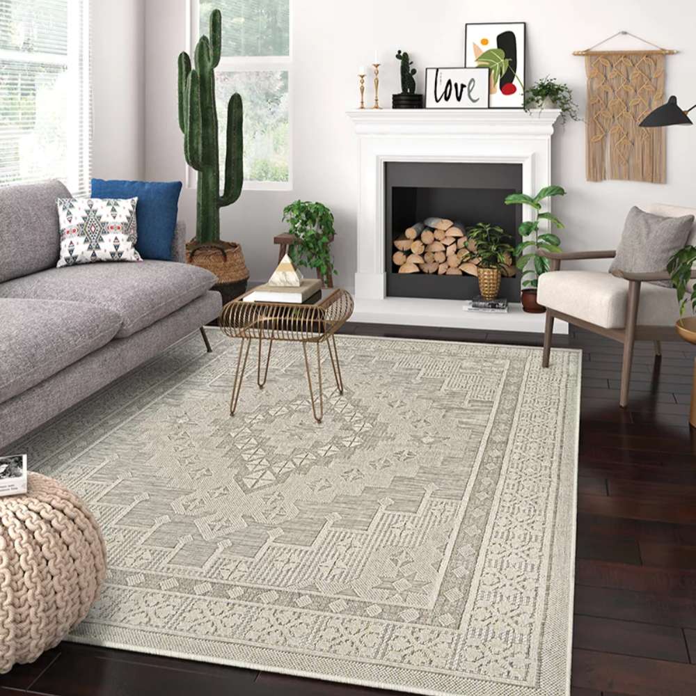 A cozy living room setup featuring a sofa, chair, and fireplace with Couristan Liguria Indoor/Outdoor Rug - Sarzana/Dove Grey as the centerpiece