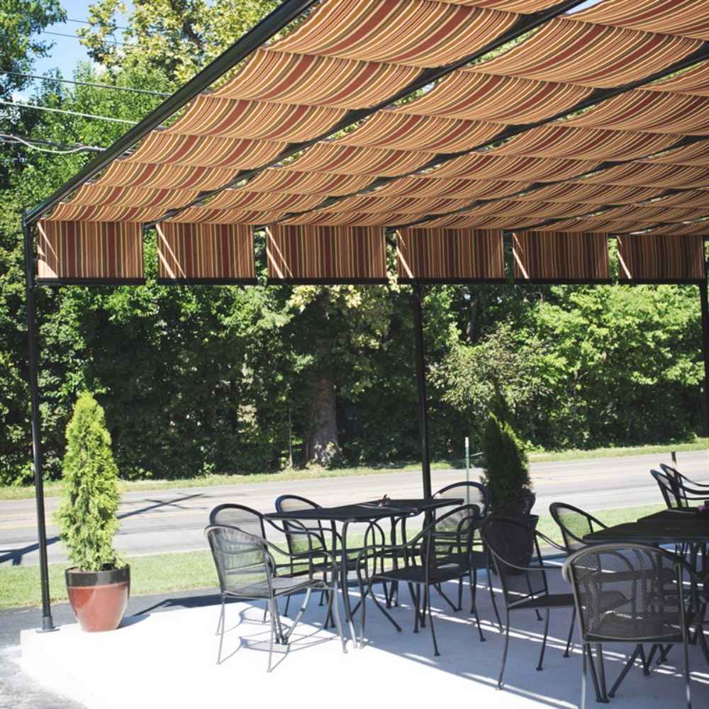 A cozy outdoor café area is shaded by a striped Structureworks Silhouette Aluminum Patio Cover & Pergola with sturdy black framing