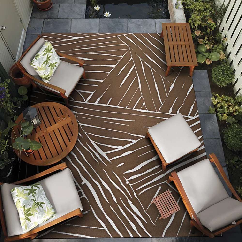 A cozy patio scene features Couristan Dolce Indoor/Outdoor Rug - Parquet/Amber under wooden outdoor furniture