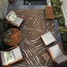 A cozy patio scene features Couristan Dolce Indoor/Outdoor Rug - Parquet/Amber under wooden outdoor furniture