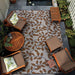 A cozy patio setup with chairs and a table sits atop Couristan Dolce Indoor/Outdoor Rug - Summer Ivy/Ivory-Terra-Cotta