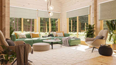 A cozy, sunlit living room with green and beige furnishings surrounded by large forest-view windows inside the GardenHouse24 USA Olivia 90 Garden Room