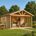 A cozy wooden garden room with sliding glass doors and a shaded porch showcases the GardenHouse24 USA ALU Concept Arosa 70C Garden Room in a green backyard setting