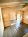 A different angle of the unfinished Sawmill Structures The Versa 240 70MM Garden Room shows two connected open spaces with natural wood walls and floors