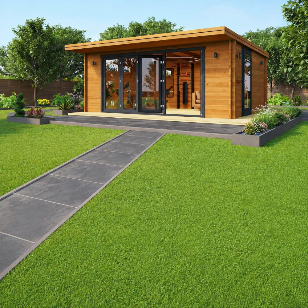 A landscaped garden surrounds the GardenHouse24 USA Paul 70 Garden Room, which is staged as a home gym with bright interior lighting and fitness equipment