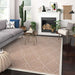 A living room setup features Couristan Liguria Indoor/Outdoor Rug - Noli/Umber beneath a gray sofa, fireplace, and plants
