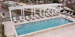 A minimalist Structureworks Williamsburg Fiberglass Pergola lines a rooftop terrace, casting shadows over poolside seating with a city view