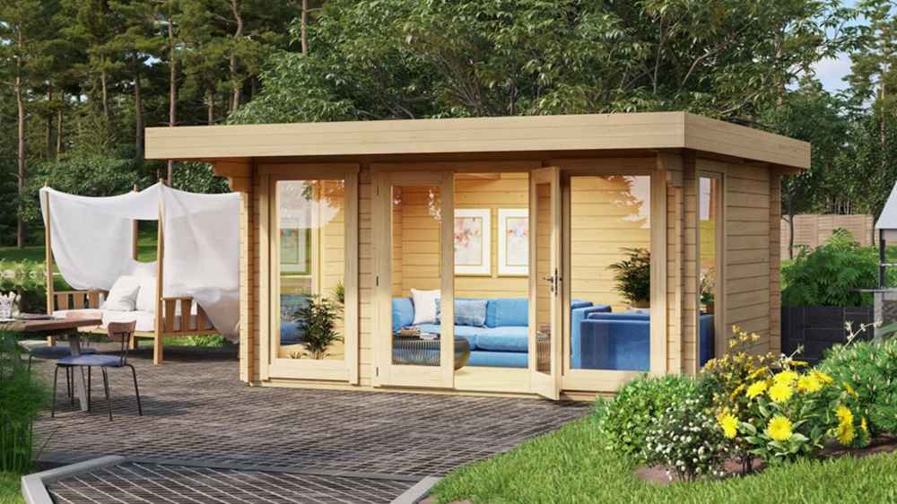 A modern, light-wood GardenHouse24 USA Barbara 44A Garden Room with wide glass doors and windows, a blue sectional sofa inside, and surrounded by lush greenery