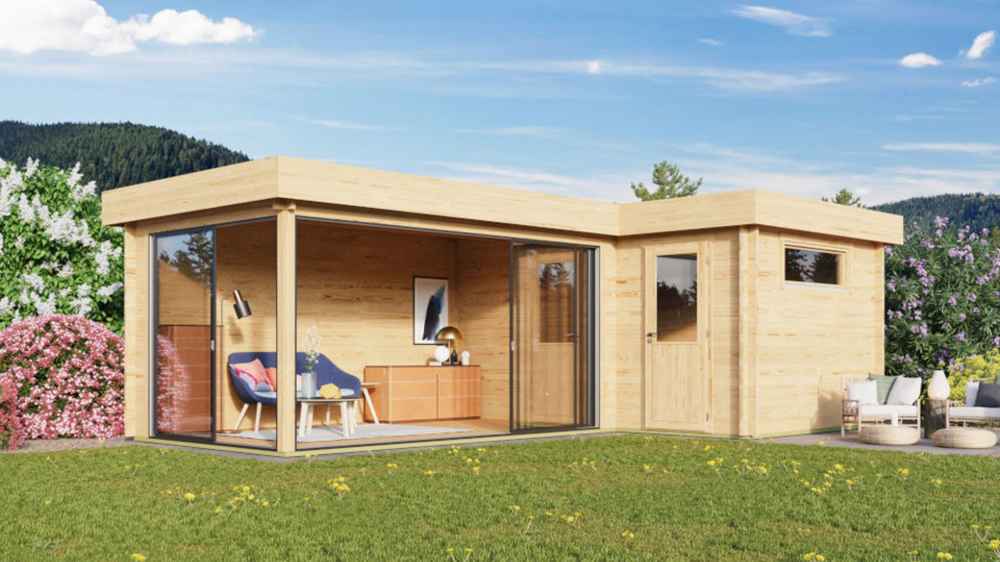 A modern, light-wood structure with large glass sliding doors opens to a furnished corner lounge, showcasing the GardenHouse24 USA ALU Concept 70N Garden Room in a blooming garden setting