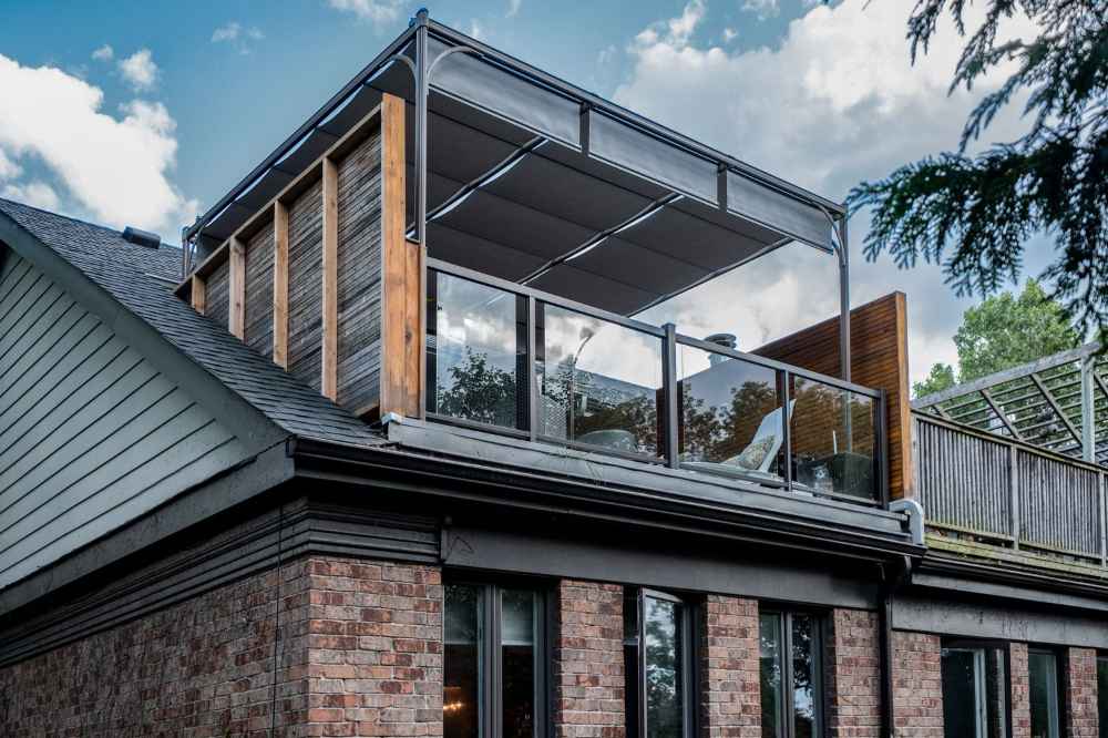 A modern rooftop lounge features a sleek Structureworks Silhouette Aluminum Patio Cover & Pergola with glass railings and shaded seating