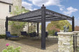 A paved courtyard beside a stone house furnished with dark blue patio furniture beneath a striped Structureworks Windsor Aluminum Patio Cover