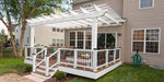A raised backyard deck connects to a home and is covered by a classic white Structureworks Trex Pergola with railing