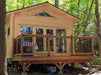 A raised deck with black railing leads to the glass double doors of the Sawmill Structures Edwin Lake House 70MM Garden Room