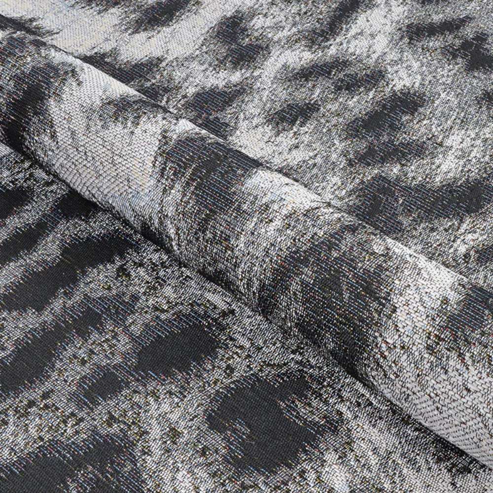 A rolled portion of Couristan Dolce Indoor/Outdoor Rug - Lynx/Ivory-Charcoal reveals its flexible fabric and soft black and ivory texture