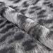 A rolled portion of Couristan Dolce Indoor/Outdoor Rug - Lynx/Ivory-Charcoal reveals its flexible fabric and soft black and ivory texture