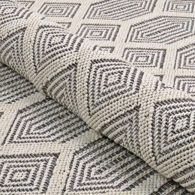 A rolled section of Couristan Liguria Indoor/Outdoor Rug - Rapallo/Pebble highlights its thick weave and geometric design