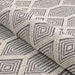A rolled section of Couristan Liguria Indoor/Outdoor Rug - Rapallo/Pebble highlights its thick weave and geometric design