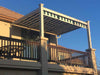 A second-story balcony is shaded by a striped retractable awning within a sleek, white-framed Structureworks Craftsman Aluminum Patio Cover & Pergola