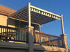 A second-story balcony is shaded by a striped retractable awning within a sleek, white-framed Structureworks Craftsman Aluminum Patio Cover & Pergola