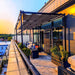A sunset view enhances a rooftop deck with a contemporary Structureworks Silhouette Aluminum Patio Cover & Pergola over lounge furniture and potted plants