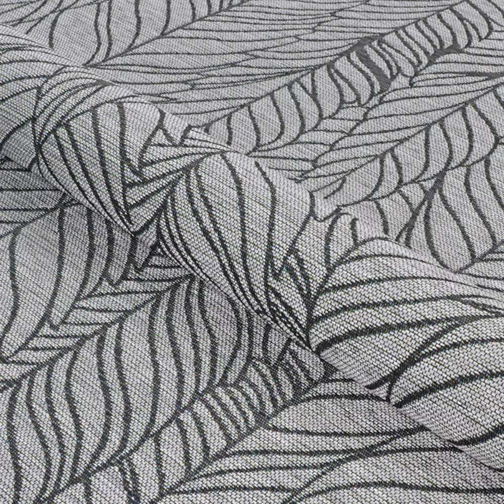 A textured view of Couristan Dolce Indoor/Outdoor Rug - Majorelle/Silver-Black shows its flexible material with soft folds and detailed black leaf outlines