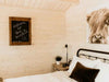 A welcoming sign on a chalkboard and rustic decor above a bed in the Sawmill Structures Harvest Grand Bungalow 107 Garden Room