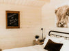 A welcoming sign on a chalkboard and rustic decor above a bed in the Sawmill Structures Harvest Grand Bungalow 107 Garden Room